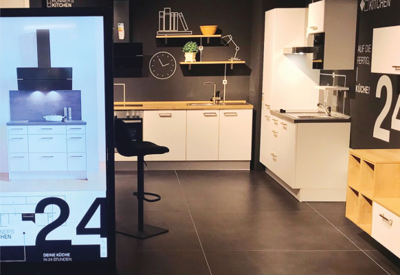 Showroom-Küche mit großem Bildschirm, umgeben von stilvollen Küchenelementen